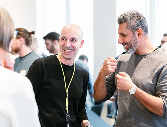Gesprächsrunde bei einem Team-Event mit Publikum im Hintergrund und Mikrofon in der Diskussion.